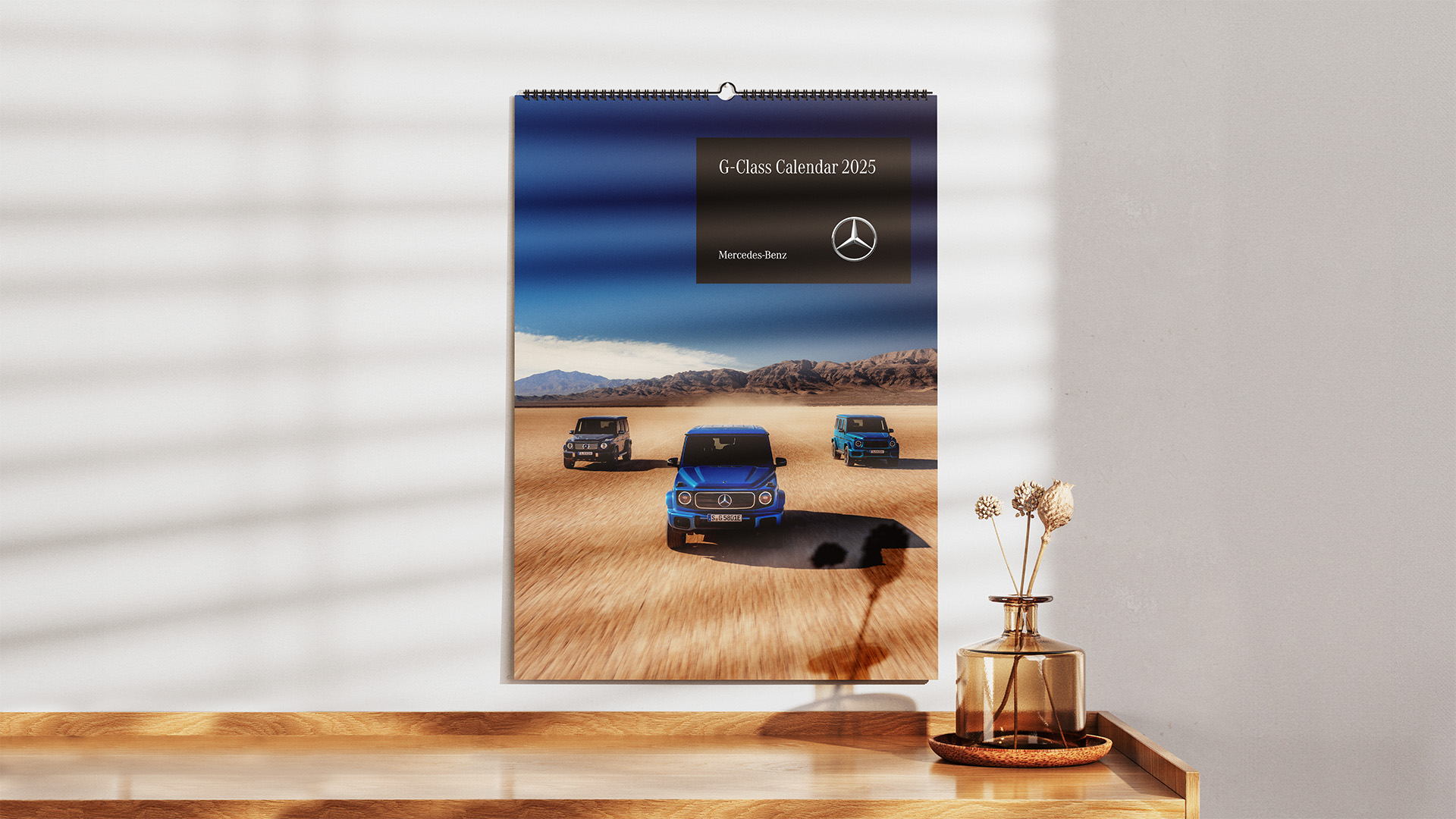 Entdecken Sie den Mercedes-Benz Kalender Shop Wandkalender 2025 mit beeindruckenden Aufnahmen der G-Klasse im Gelände. Dieses Bild zeigt die G-Klasse in der Wüste, perfekt für alle Liebhaber von robusten Geländewagen.